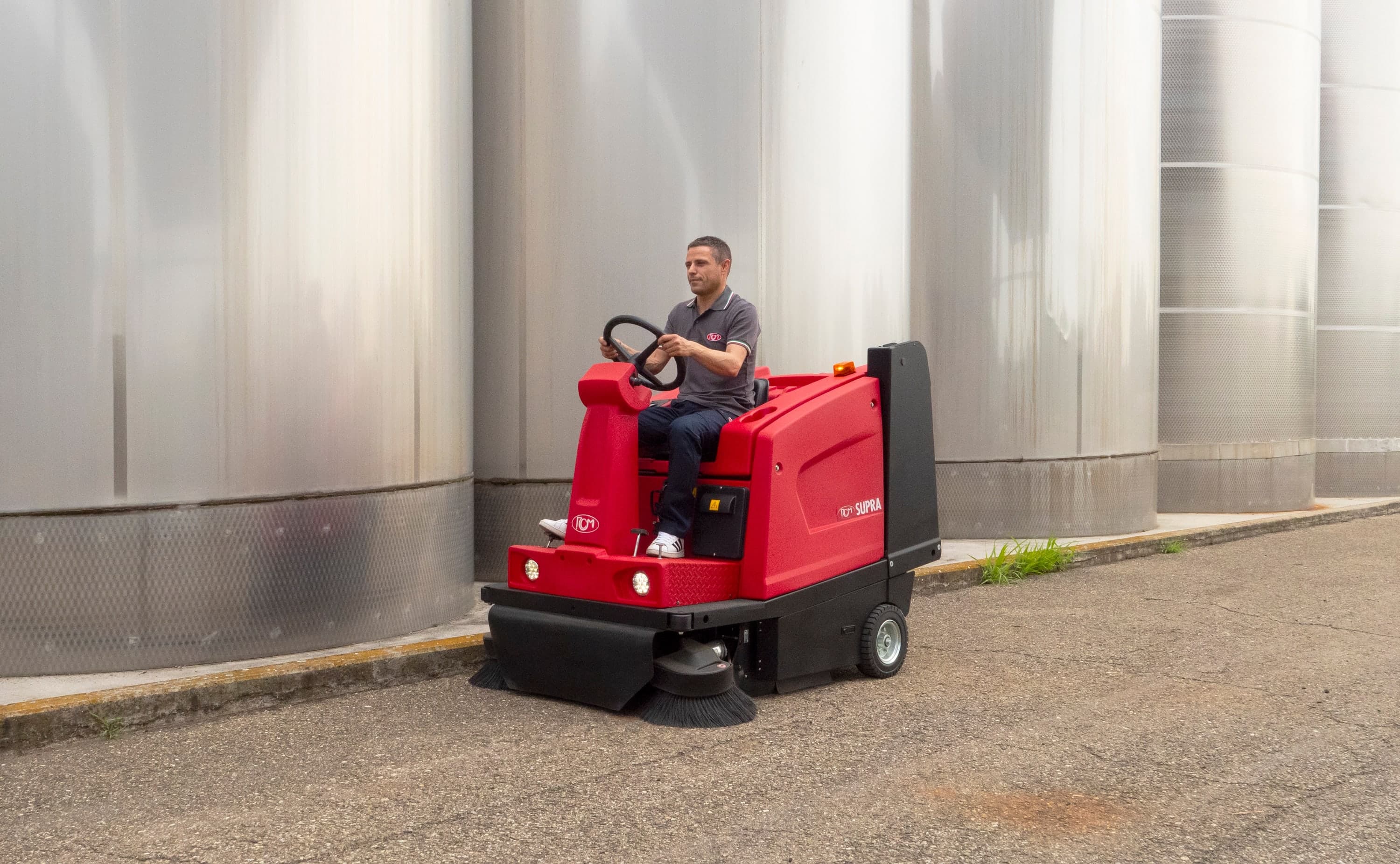 RCM SUPRA Aufsitz-Kehrsaugmaschine vor Edelstahltanks eines Industriebetriebs